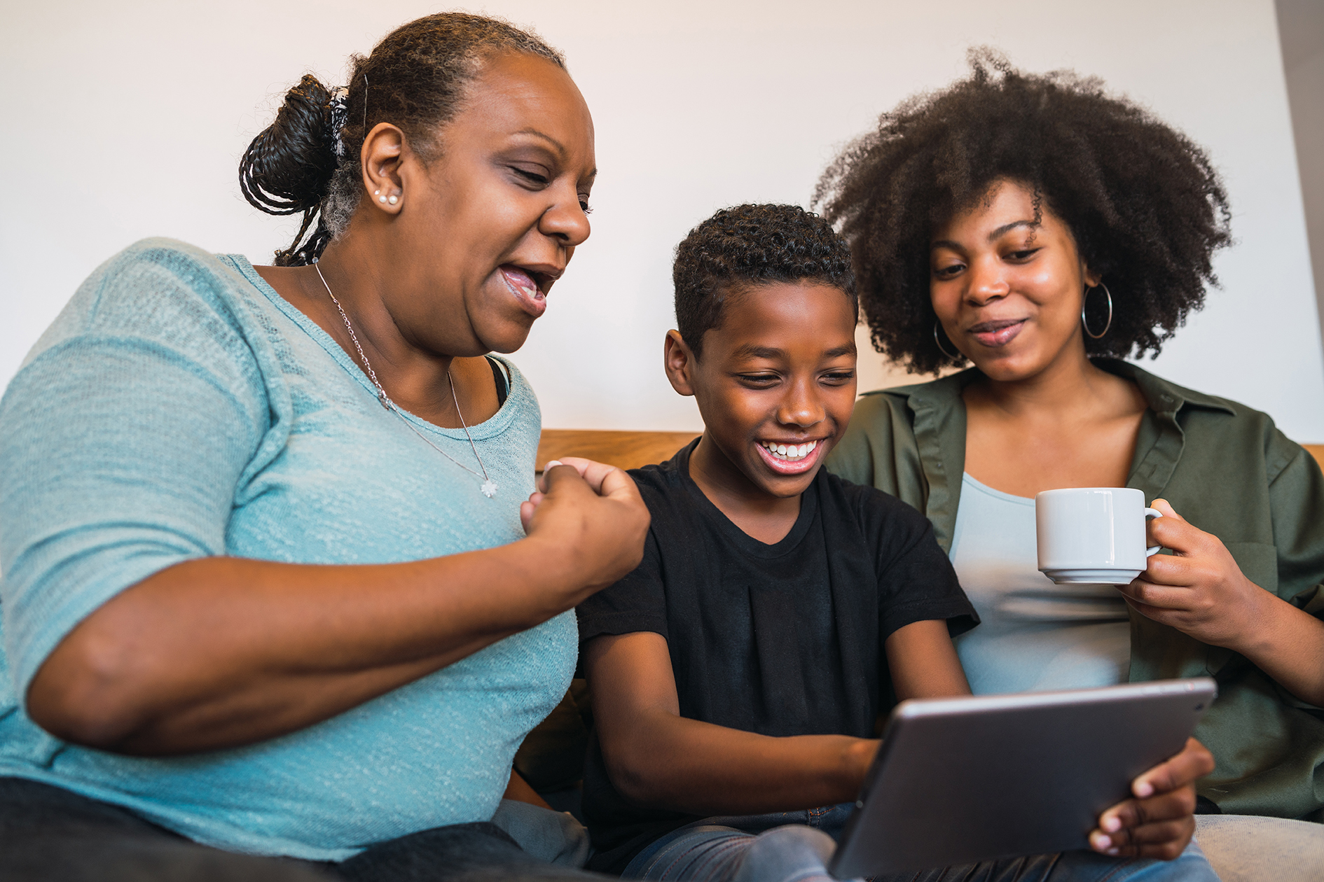 Portrait of African American grandmother, mother and son taking a selfie with digital tablet at home. Technology and lifestyle concept.